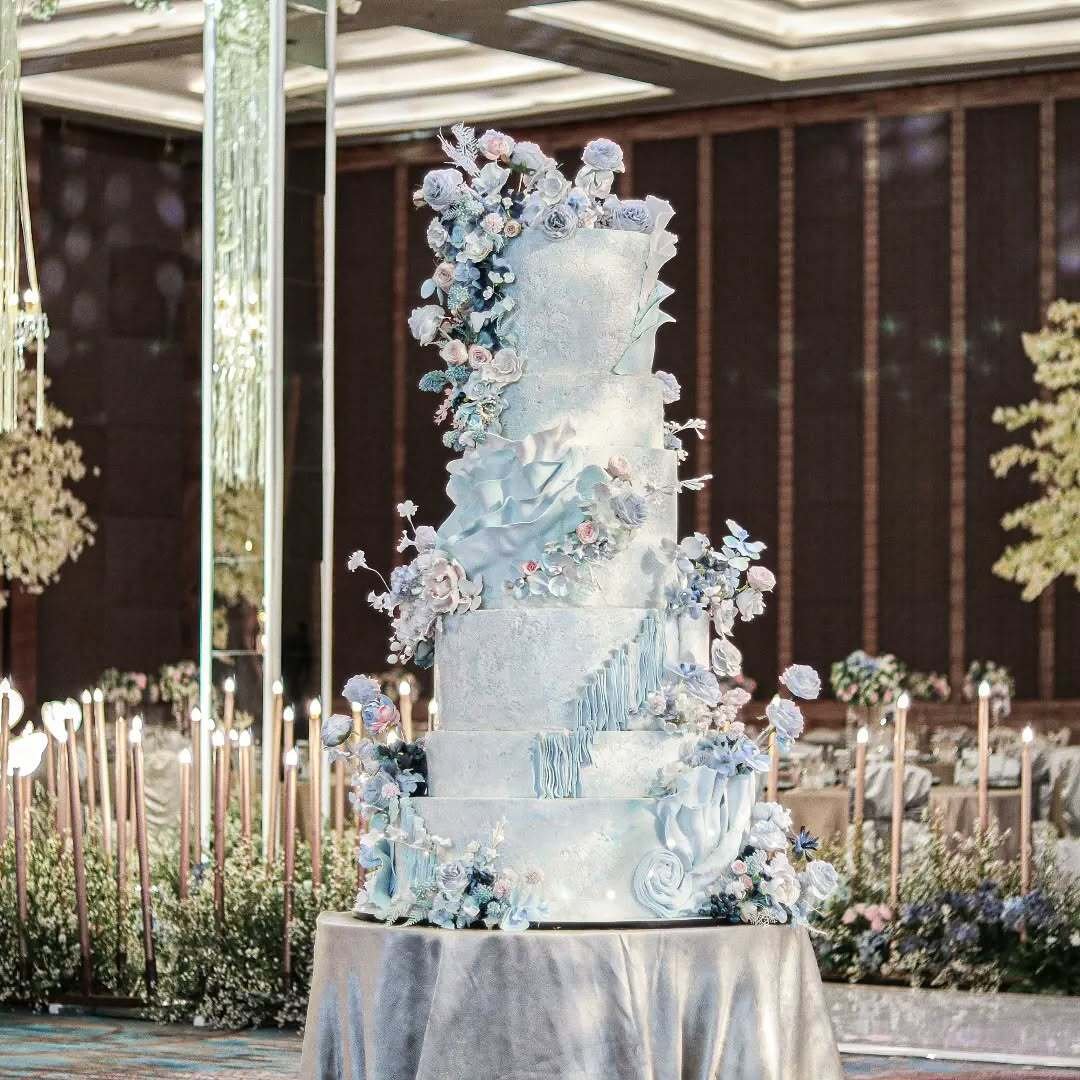 Multi-tier wedding cake with blue and white floral decorations.