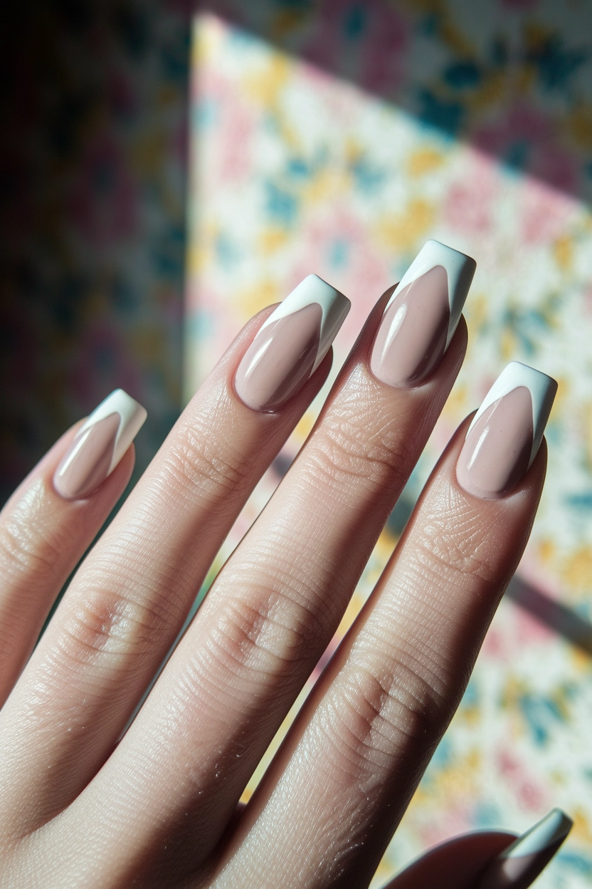 a neutral base and white V-shaped French tips, displayed against a background with soft floral patterns.