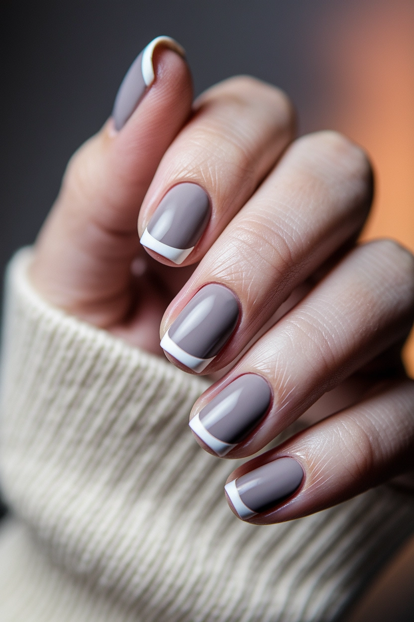 a grey base and white French tips, displayed against a soft, textured fabric.