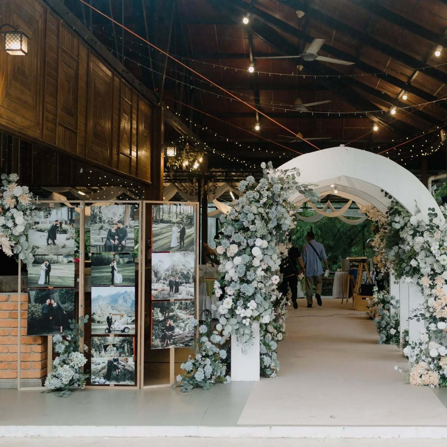 A large white wedding arch heavily decorated with white and pale green hydrangeas, and various sage green foliage, creating a lush floral display.