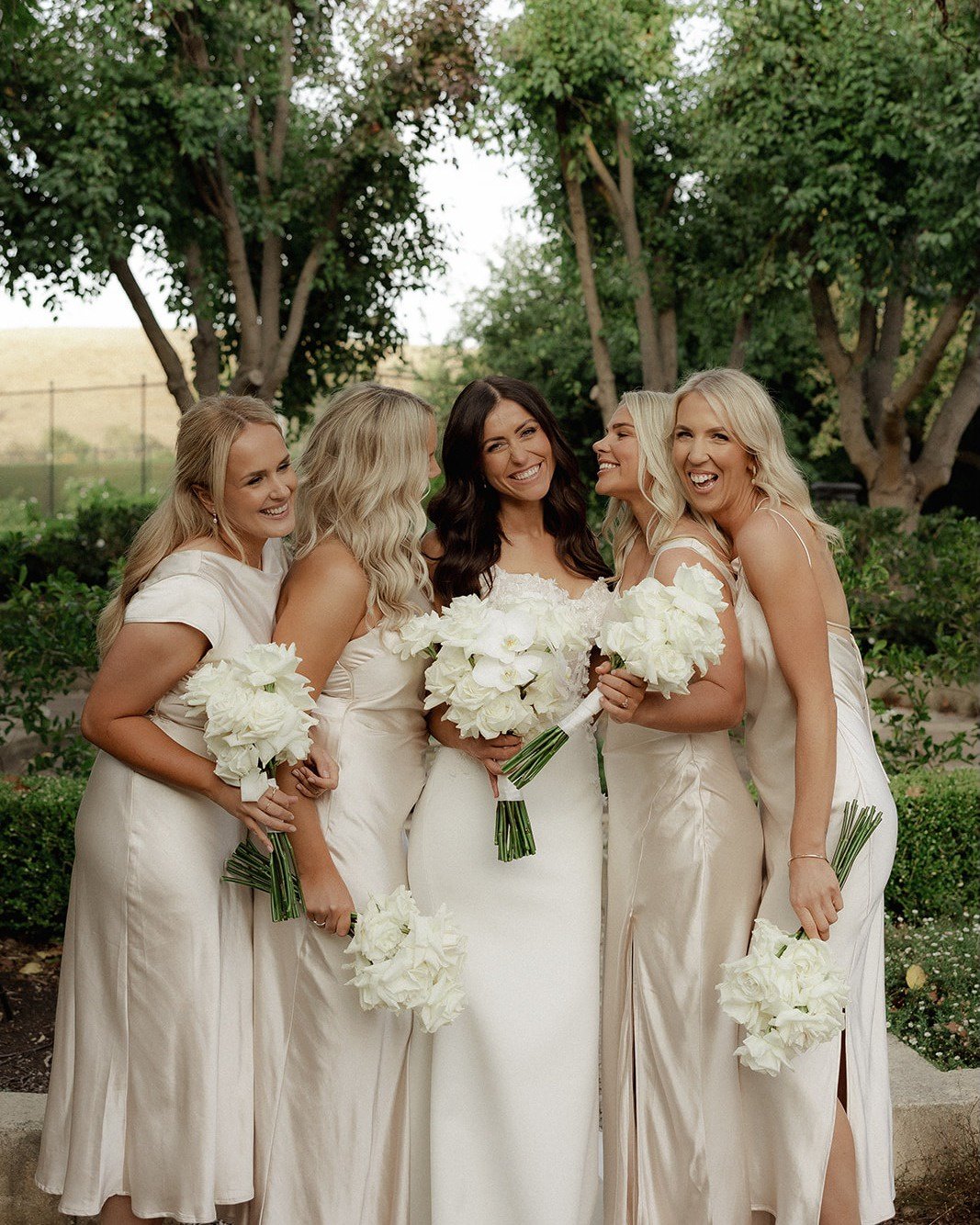 Bride and bridesmaids holding matching white flower bouquets.