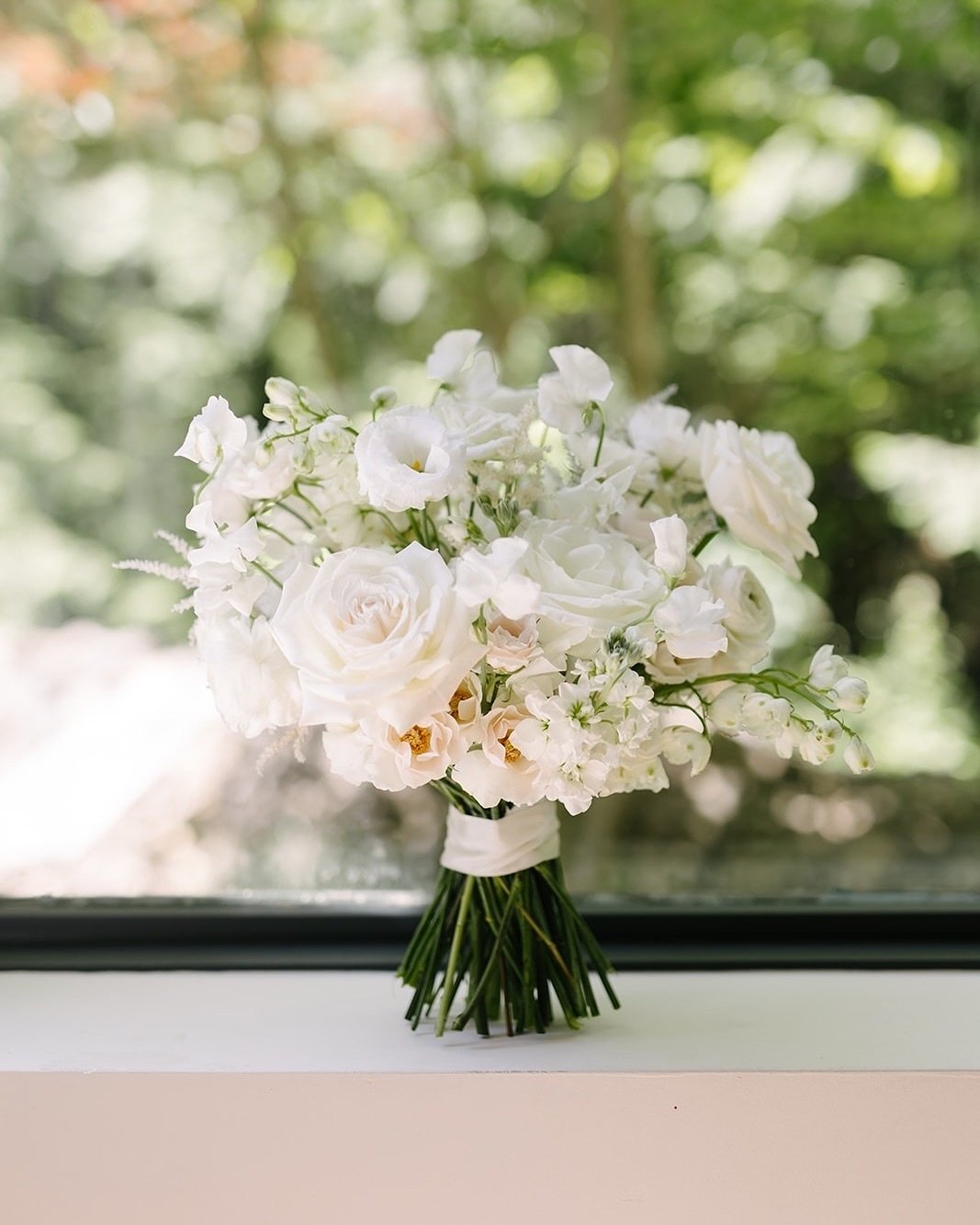 Close-up of a white wedding bouquet with roses and other white flowers.