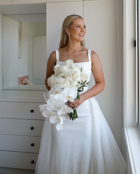 Bride holding a bouquet of white roses and orchids.