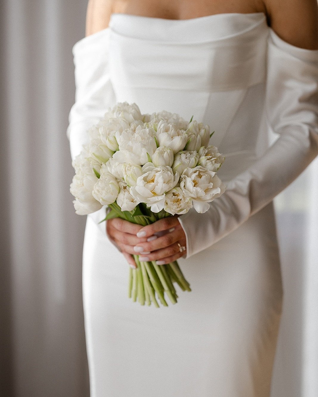 Bride holding a bouquet of white tulips.